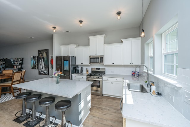 kitchen featuring sink, white cabinetry, a center island, pendant lighting, and stainless steel appliances