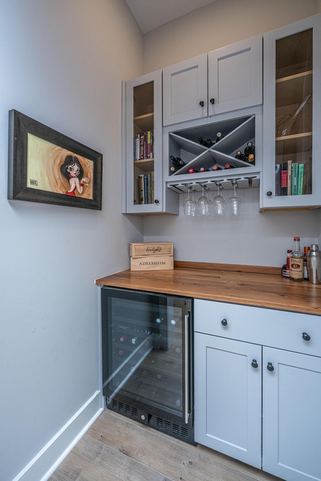 bar with white cabinetry, beverage cooler, wood counters, and light hardwood / wood-style floors