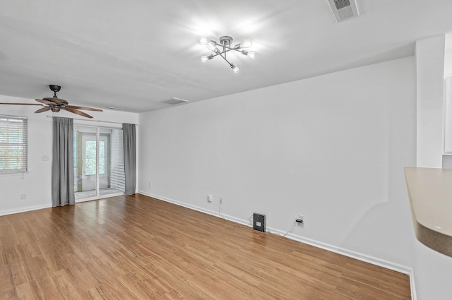 unfurnished room featuring light hardwood / wood-style flooring and ceiling fan with notable chandelier