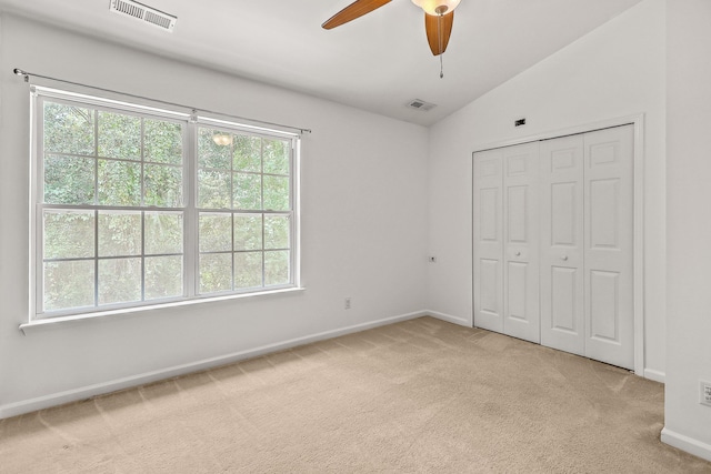 unfurnished bedroom with ceiling fan, a closet, light carpet, and vaulted ceiling