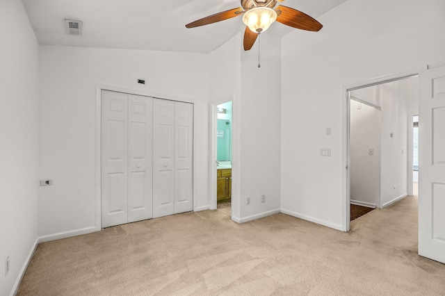 unfurnished bedroom with light carpet, ensuite bathroom, ceiling fan, a closet, and lofted ceiling