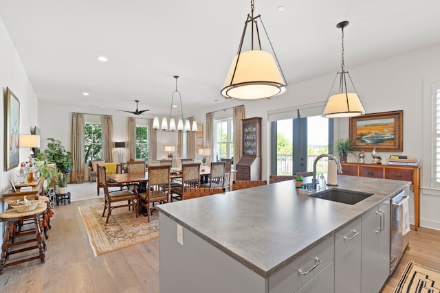 kitchen featuring a healthy amount of sunlight, sink, light wood-type flooring, and a kitchen island with sink