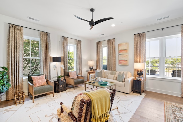 living room with light hardwood / wood-style flooring, ceiling fan, and a healthy amount of sunlight