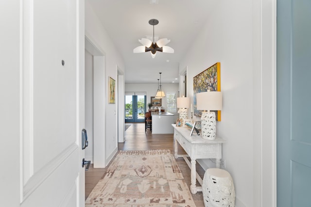 hallway with light hardwood / wood-style flooring and a notable chandelier