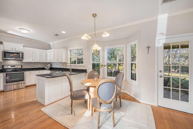 kitchen featuring white cabinetry, stainless steel appliances, and decorative light fixtures