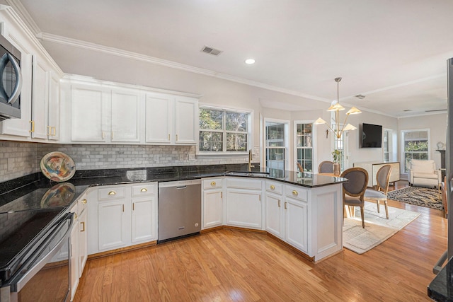 kitchen featuring sink, white cabinetry, hanging light fixtures, stainless steel appliances, and light hardwood / wood-style floors