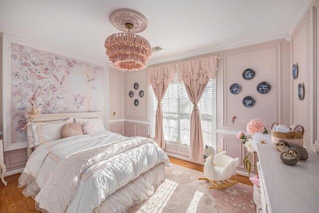 bedroom featuring ornamental molding, a chandelier, and light wood-type flooring