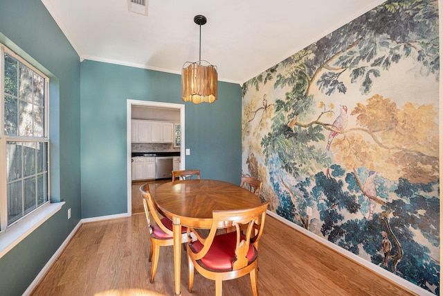 dining room with crown molding, a chandelier, and light hardwood / wood-style flooring