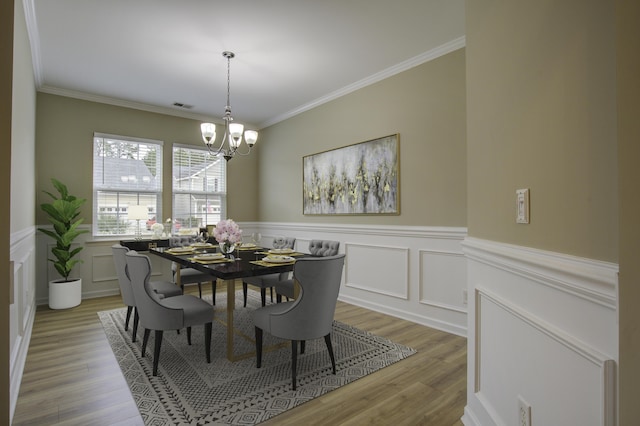 dining area featuring ornamental molding, light wood-type flooring, and a chandelier