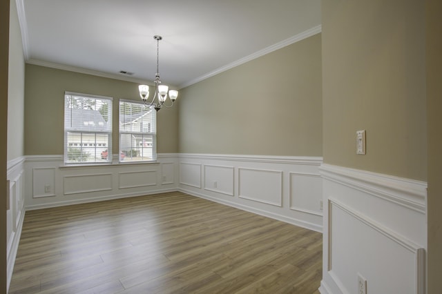 spare room featuring crown molding, light hardwood / wood-style floors, and a notable chandelier