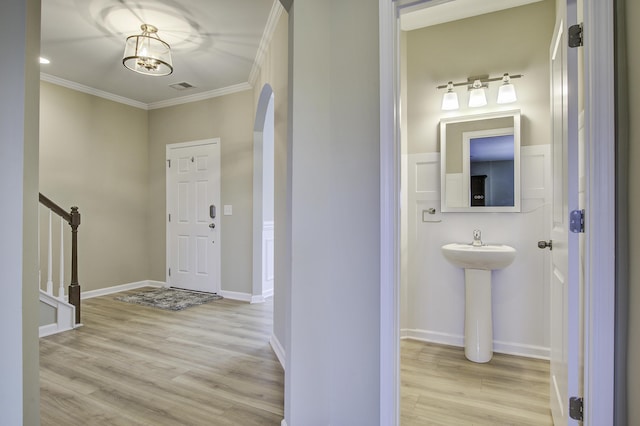 entrance foyer featuring sink, a notable chandelier, crown molding, and light hardwood / wood-style flooring