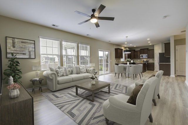 living room with light wood-type flooring and ceiling fan