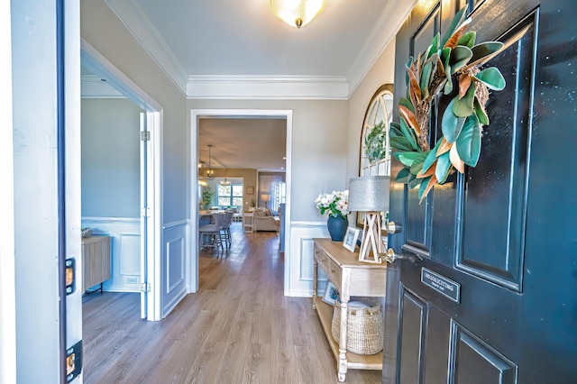 entryway featuring a decorative wall, wainscoting, light wood-type flooring, and crown molding