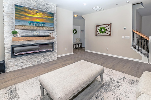 living area featuring visible vents, baseboards, recessed lighting, a fireplace, and wood finished floors