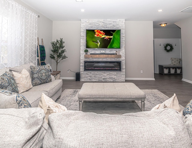 living area with a fireplace, wood finished floors, visible vents, and baseboards