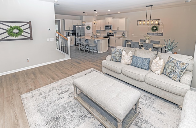 living room featuring a chandelier, recessed lighting, baseboards, and wood finished floors