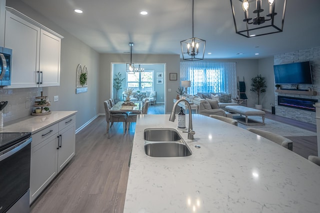 kitchen with light stone countertops, open floor plan, appliances with stainless steel finishes, an inviting chandelier, and a sink