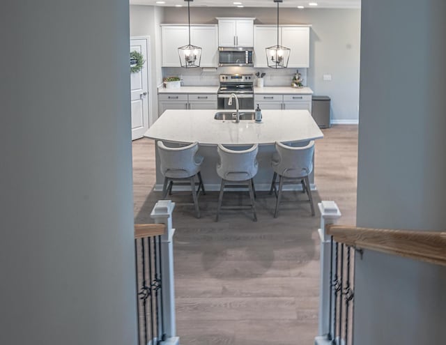 kitchen featuring backsplash, appliances with stainless steel finishes, light countertops, and light wood-style floors