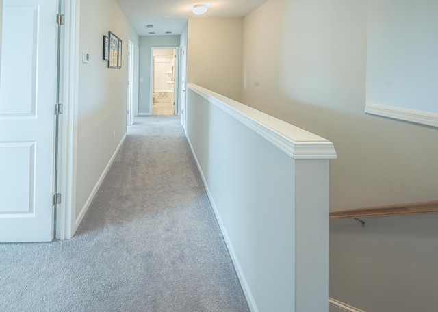 hall with baseboards and light carpet