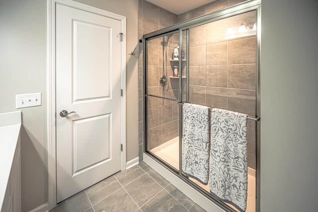 bathroom with tile patterned flooring, baseboards, and tiled shower