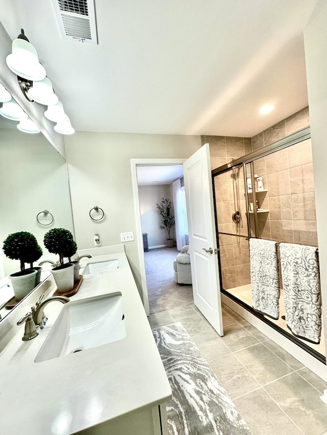 full bathroom with double vanity, visible vents, a stall shower, and a sink