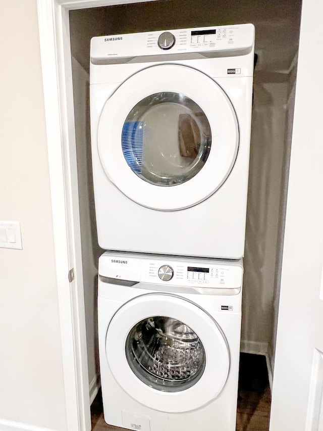 clothes washing area featuring hardwood / wood-style flooring and stacked washer / dryer