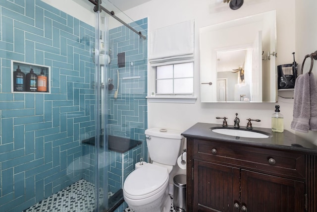 bathroom featuring a shower with door, vanity, and toilet