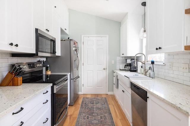 kitchen with sink, white cabinetry, appliances with stainless steel finishes, pendant lighting, and light stone countertops