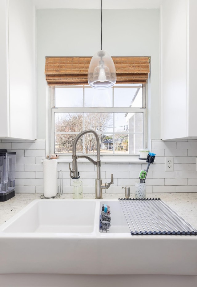 room details featuring white cabinetry, sink, light stone countertops, and hanging light fixtures