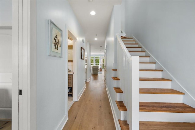 stairway featuring baseboards, wood finished floors, and recessed lighting