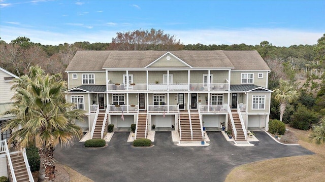 view of front of house featuring a balcony, a standing seam roof, stairs, and covered porch