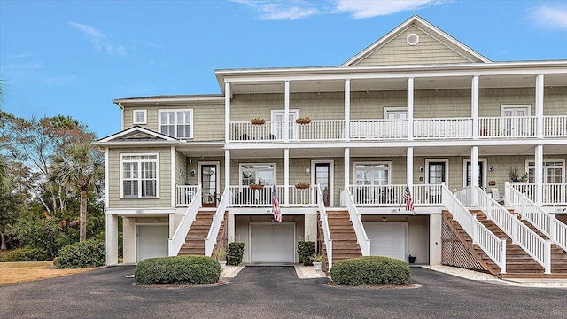 view of front of home featuring aphalt driveway, covered porch, stairway, and a garage