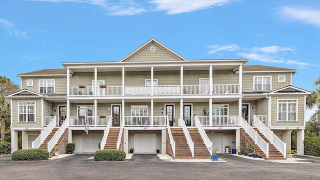 view of front facade with a balcony, covered porch, a garage, driveway, and stairway