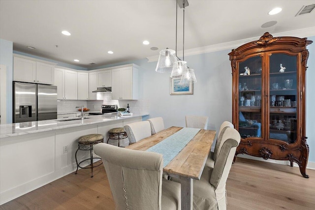 dining space with light wood-style floors, recessed lighting, visible vents, and crown molding