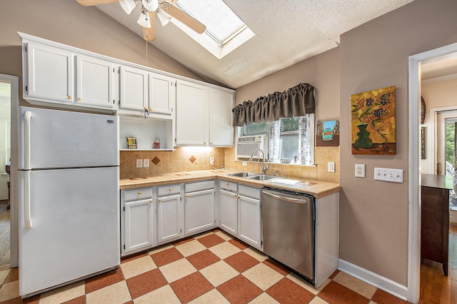 kitchen featuring freestanding refrigerator, dishwasher, a skylight, a sink, and ceiling fan