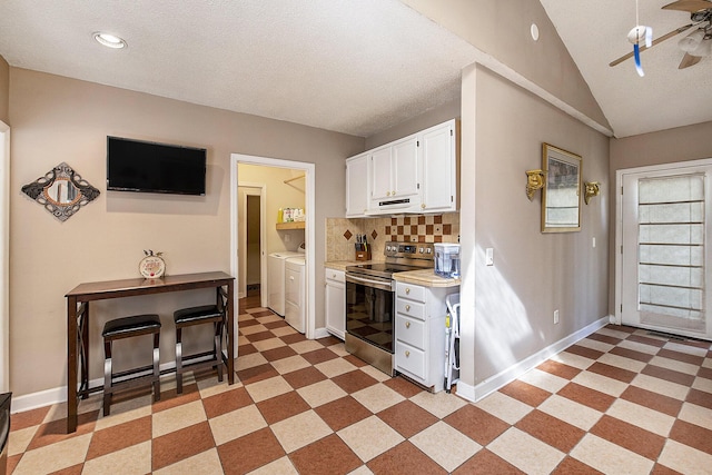 kitchen with electric range, washer and clothes dryer, white cabinets, light countertops, and a ceiling fan
