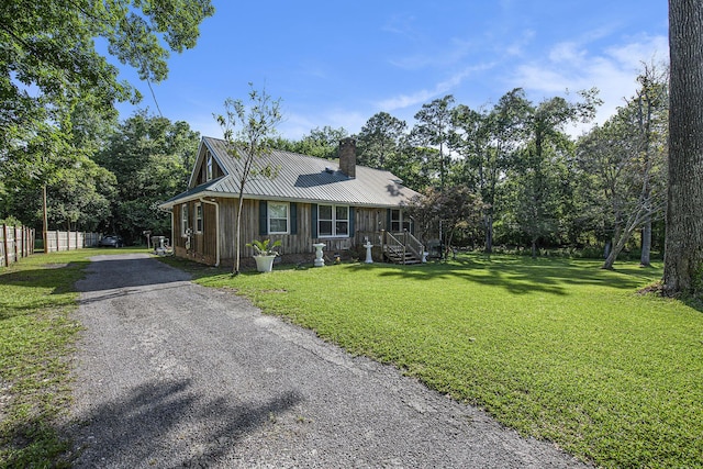 view of front of property featuring a chimney, asphalt driveway, metal roof, and board and batten siding