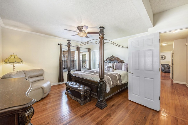 bedroom featuring a textured ceiling, hardwood / wood-style floors, crown molding, ceiling fan, and baseboards