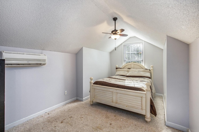 bedroom with a wall mounted AC, vaulted ceiling, a textured ceiling, baseboards, and light carpet