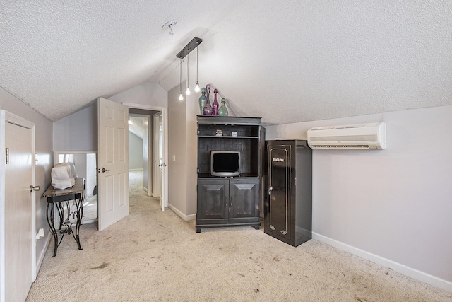 living area featuring vaulted ceiling, a wall mounted air conditioner, a textured ceiling, carpet floors, and baseboards