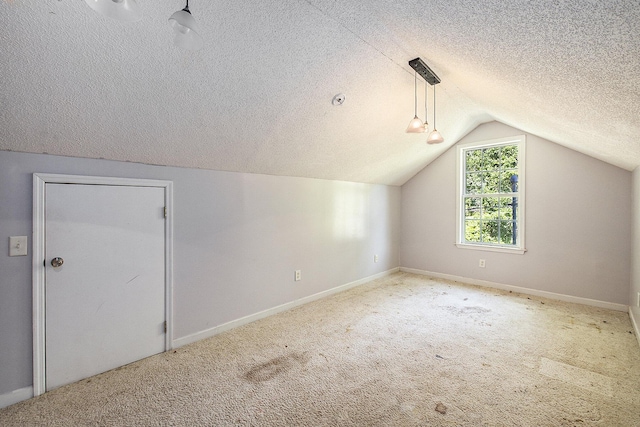 additional living space with a textured ceiling, lofted ceiling, baseboards, and carpet
