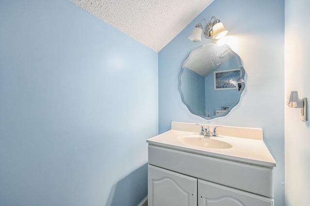bathroom with a textured ceiling, vaulted ceiling, and vanity