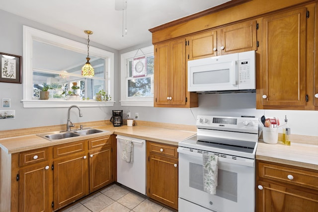kitchen featuring light countertops, brown cabinets, a sink, and white appliances
