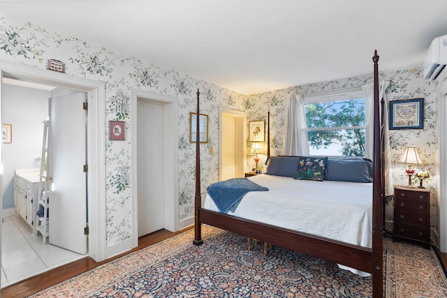 bedroom with wallpapered walls, wood finished floors, and a wall mounted air conditioner