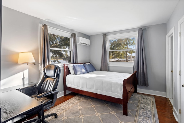 bedroom with baseboards, wood finished floors, a wall unit AC, and multiple windows