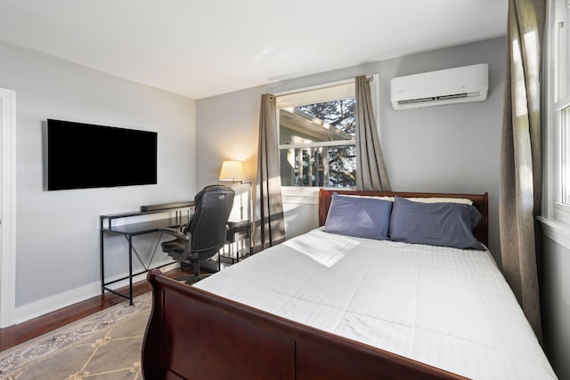 bedroom featuring baseboards, wood finished floors, and a wall mounted AC