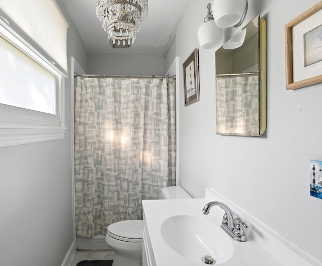 bathroom featuring curtained shower, toilet, vanity, and an inviting chandelier