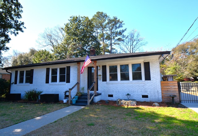 view of front facade with brick siding, a front lawn, fence, a chimney, and crawl space