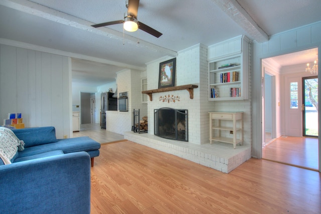 living room featuring built in features, a fireplace, beamed ceiling, wood-type flooring, and ornamental molding