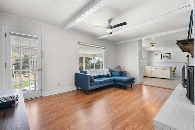 living room featuring beam ceiling, ceiling fan, a textured ceiling, and light hardwood / wood-style flooring